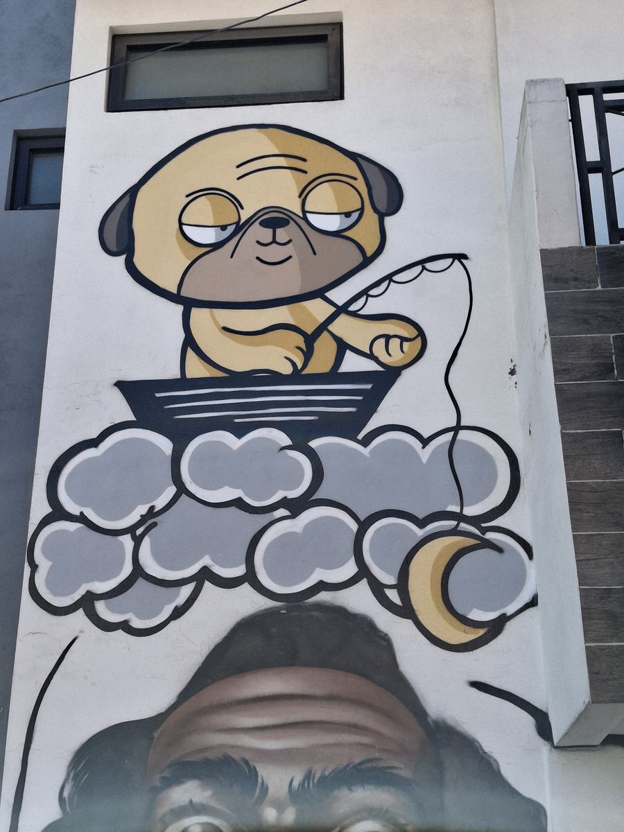 Mural de un pug soñoliento pescando desde una barca entre nubes.