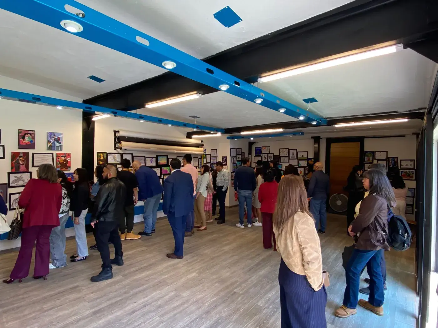 Familias y visitantes recorriendo la sala llena de obras durante la exposición.
